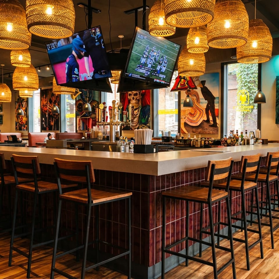 Spacious bar area with numerous woven pendant lights, bar stools, and televisions showing sports.