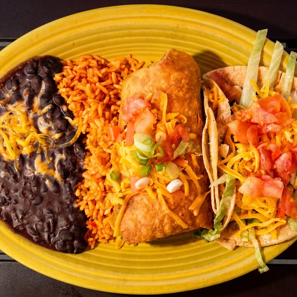 A yellow plate holds a burrito, two tacos, rice, and black beans with cheese.