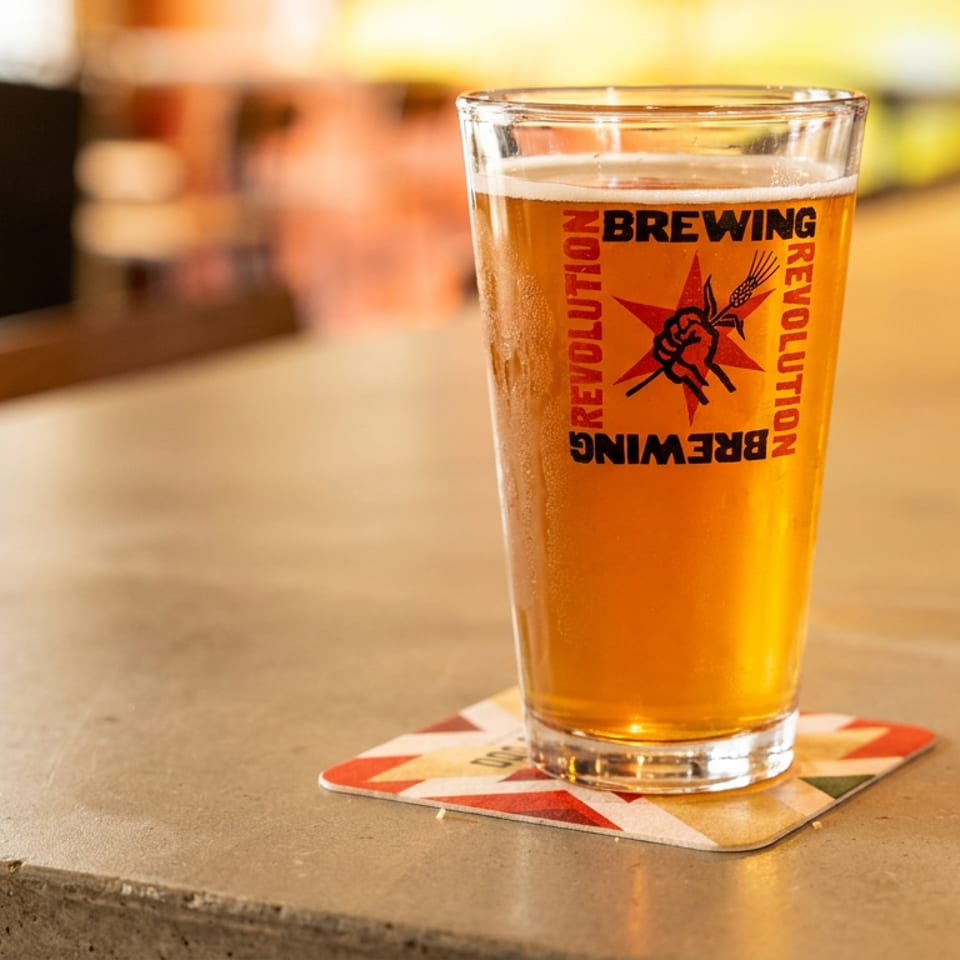 A pint glass of Revolution Brewing beer and a glass of water on a bar.